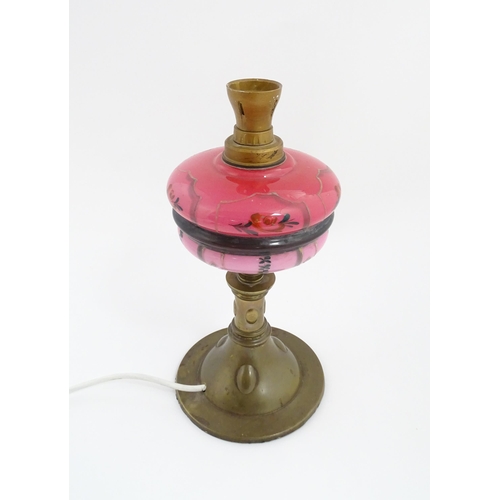 1536 - An Art & Crafts brass oil lamp with pink glass reservoir, converted to an electric table lamp. Appro... 