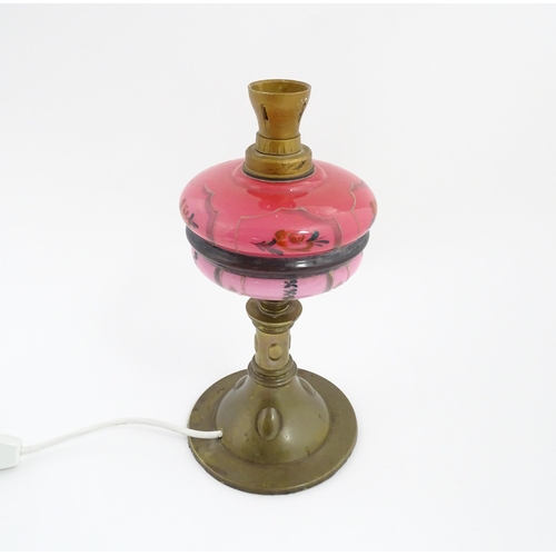 1536 - An Art & Crafts brass oil lamp with pink glass reservoir, converted to an electric table lamp. Appro... 