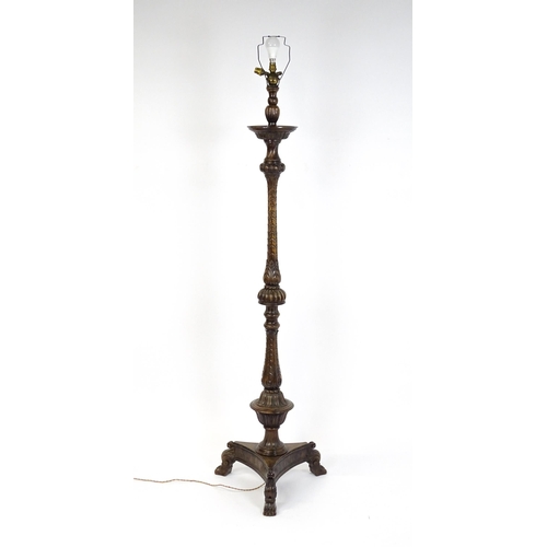 1555 - A mahogany carved and turned column standard lamp with triform base having scroll and paw feet. Appr... 