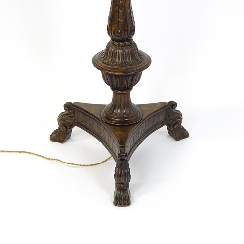 1555 - A mahogany carved and turned column standard lamp with triform base having scroll and paw feet. Appr... 