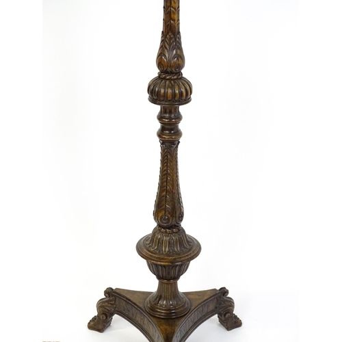 1555 - A mahogany carved and turned column standard lamp with triform base having scroll and paw feet. Appr... 