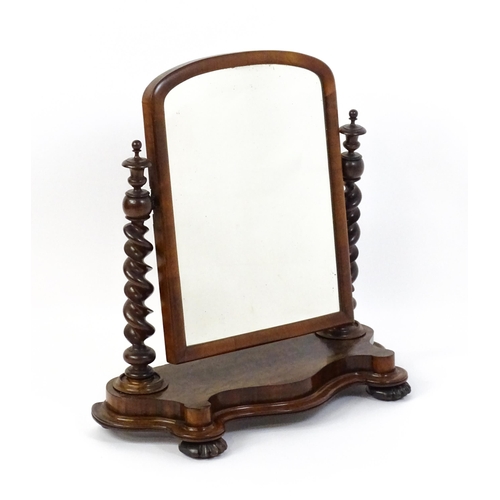 1565 - A Victorian mahogany mirror with two barley twist supports above a shaped, moulded base raised on sq... 