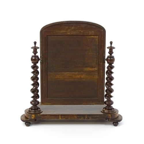 1565 - A Victorian mahogany mirror with two barley twist supports above a shaped, moulded base raised on sq... 