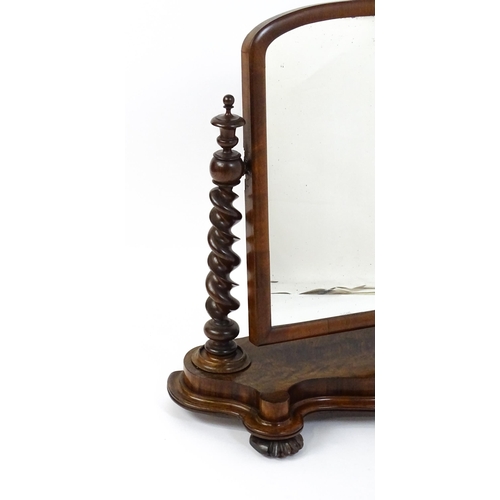 1565 - A Victorian mahogany mirror with two barley twist supports above a shaped, moulded base raised on sq... 