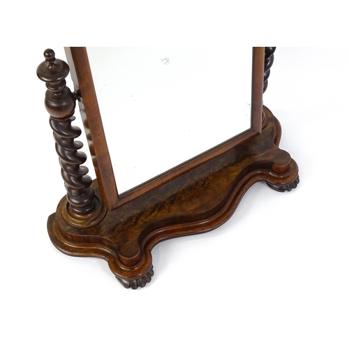 1565 - A Victorian mahogany mirror with two barley twist supports above a shaped, moulded base raised on sq... 