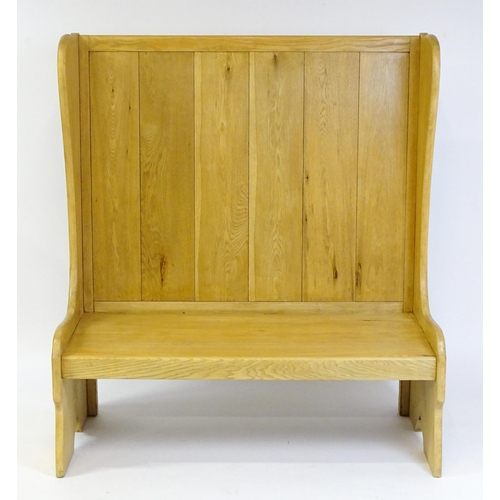 1579 - A late 20thC oak settle with a planked backrest flanked by wings and raised on shaped sides and a pl... 