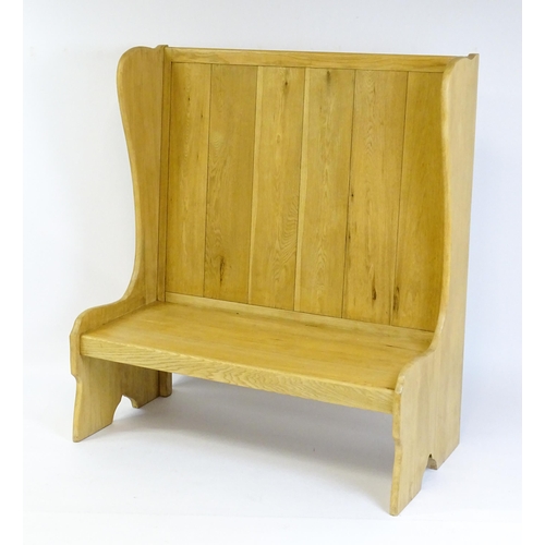 1579 - A late 20thC oak settle with a planked backrest flanked by wings and raised on shaped sides and a pl... 