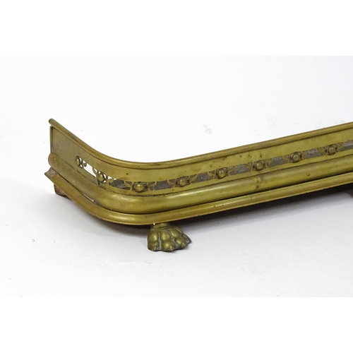 1746 - A late 19thC brass fire fender, with pierced decoration and standing on lion's paw feet, approx 47