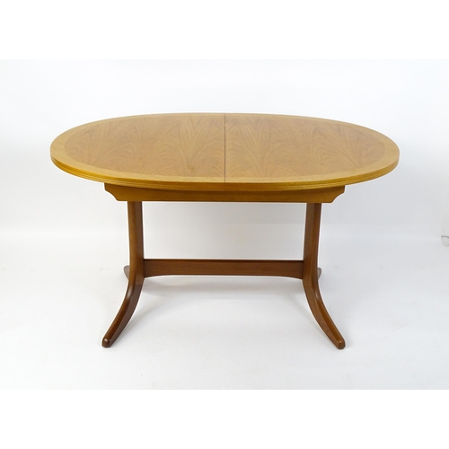 1750 - A G-Plan style teak extending dining table, the oval top supported by a pedestal base standing on fo... 