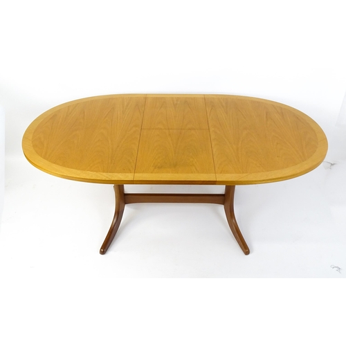 1750 - A G-Plan style teak extending dining table, the oval top supported by a pedestal base standing on fo... 