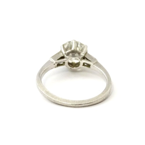 567 - A platinum set brilliant diamond solitaire ring flanked by two baguette cut diamonds to shoulders. C... 