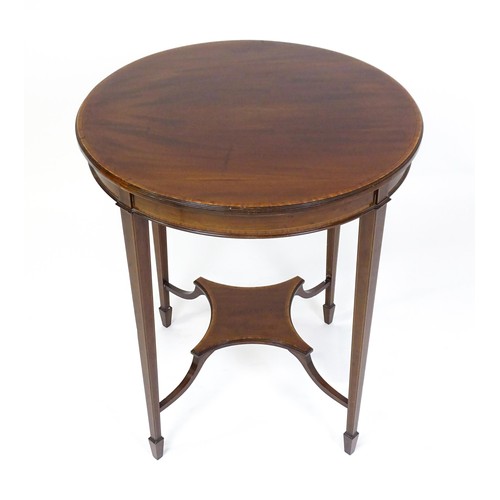 1653 - An Edwardian mahogany side table with a circular crossbanded top above a shaped under tier raised on... 