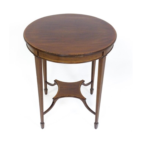 1653 - An Edwardian mahogany side table with a circular crossbanded top above a shaped under tier raised on... 