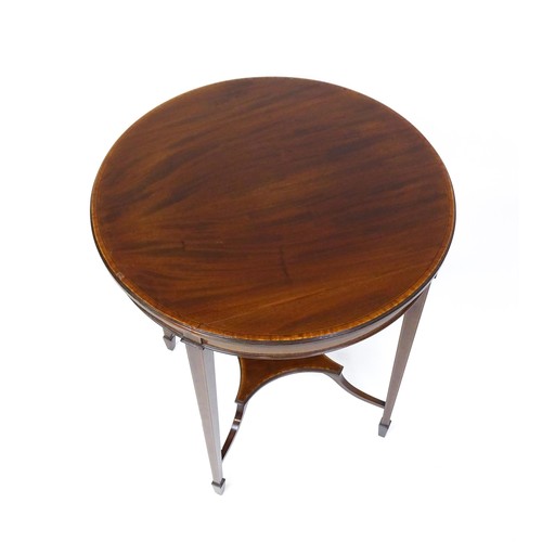 1653 - An Edwardian mahogany side table with a circular crossbanded top above a shaped under tier raised on... 