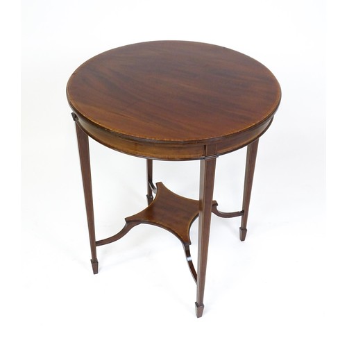 1653 - An Edwardian mahogany side table with a circular crossbanded top above a shaped under tier raised on... 