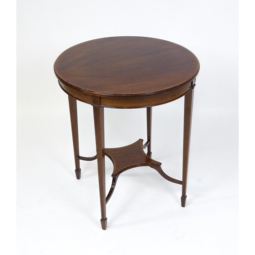 1653 - An Edwardian mahogany side table with a circular crossbanded top above a shaped under tier raised on... 