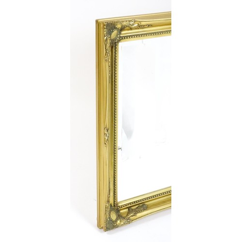 39 - A modern gilt framed mirror with floral moulded corners and beaded decoration. 42