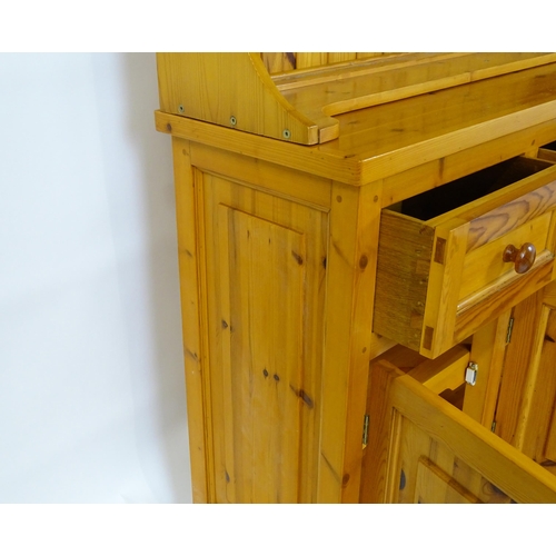 90 - A pine dresser with a three tier plate rack above three short drawers and three panelled cupboards w... 