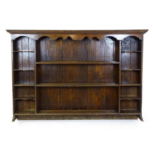 104 - An 18thC oak plate rack with a moulded frieze above two sets of five small shelves flanking three ce... 