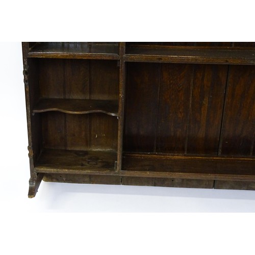 104 - An 18thC oak plate rack with a moulded frieze above two sets of five small shelves flanking three ce... 