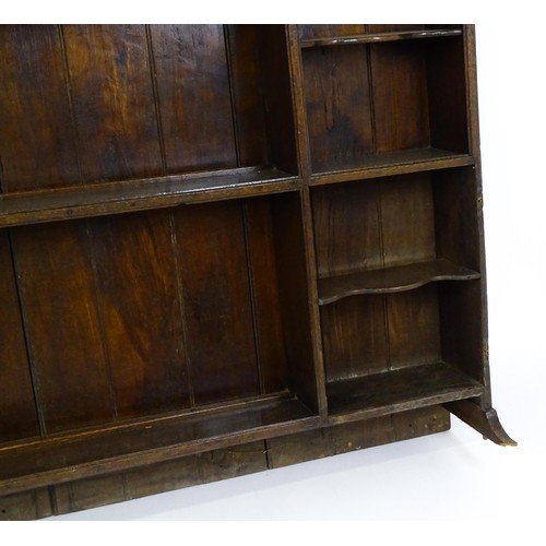 104 - An 18thC oak plate rack with a moulded frieze above two sets of five small shelves flanking three ce... 