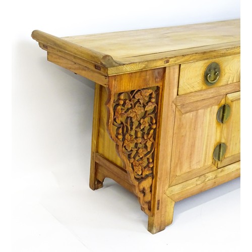 315 - A mid 20thC oriental sideboard with a planked top, shaped ends and pierced brackets to either side w... 