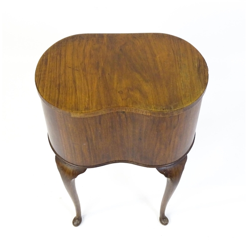328 - An early / mid 20thC walnut work box of kidney form, having a hinged lid, fabric lined interior and ... 