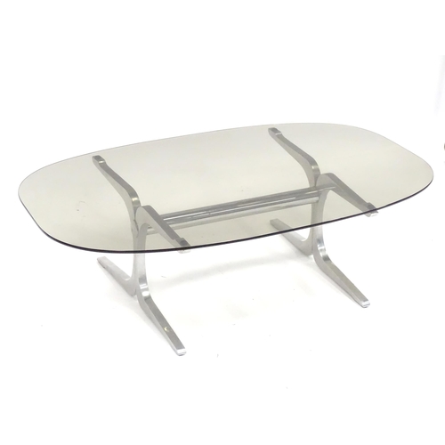 331 - A 20thC coffee table, with elliptical smoky glass top supported by a brushed aluminium frame. In the... 