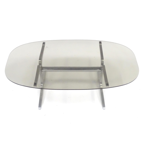331 - A 20thC coffee table, with elliptical smoky glass top supported by a brushed aluminium frame. In the... 