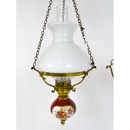 349 - Two pendant oil lamps one with ceramic reservoir with floral detail. Largest approx. 11