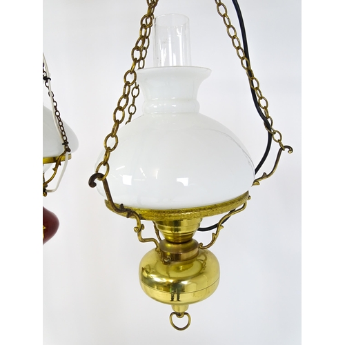349 - Two pendant oil lamps one with ceramic reservoir with floral detail. Largest approx. 11