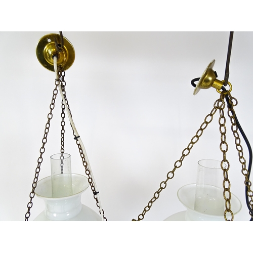 349 - Two pendant oil lamps one with ceramic reservoir with floral detail. Largest approx. 11