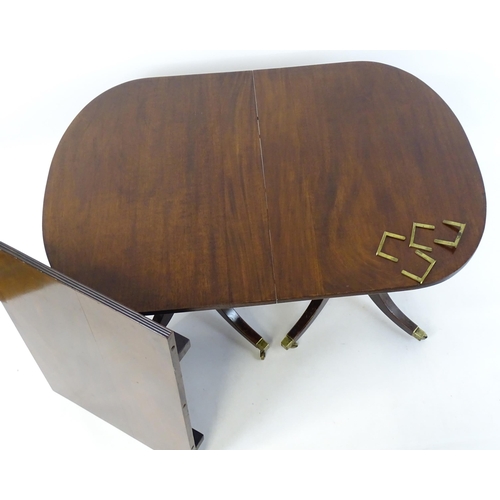 357 - A Regency style double pedestal mahogany dining table with a reeded edge and an additional leaf. Un-... 