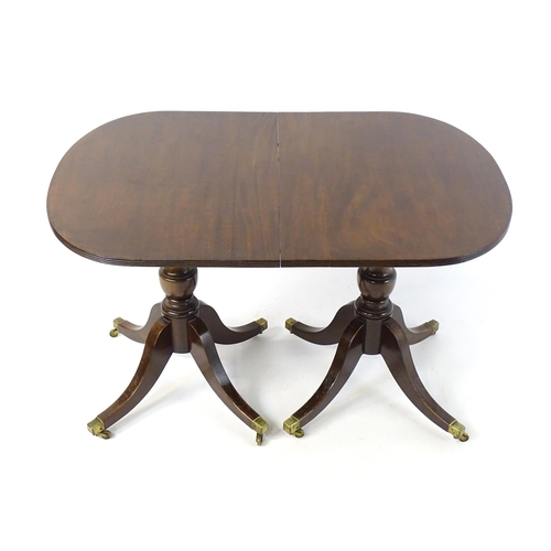 357 - A Regency style double pedestal mahogany dining table with a reeded edge and an additional leaf. Un-... 
