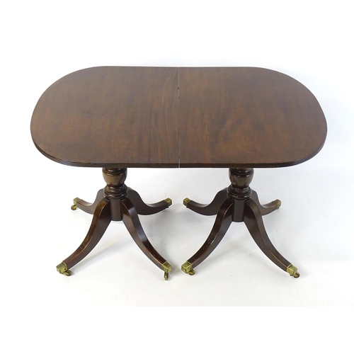 357 - A Regency style double pedestal mahogany dining table with a reeded edge and an additional leaf. Un-... 