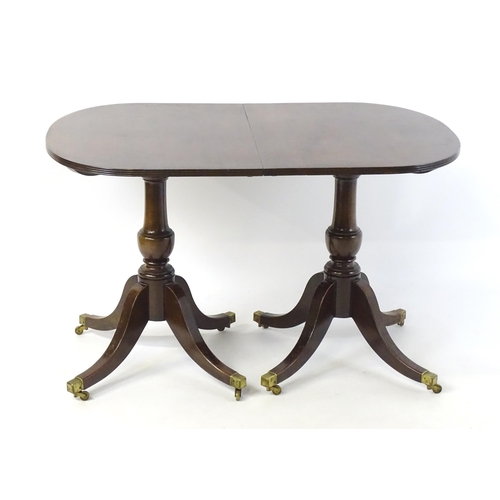 357 - A Regency style double pedestal mahogany dining table with a reeded edge and an additional leaf. Un-... 