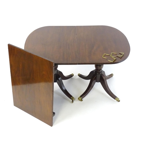 357 - A Regency style double pedestal mahogany dining table with a reeded edge and an additional leaf. Un-... 