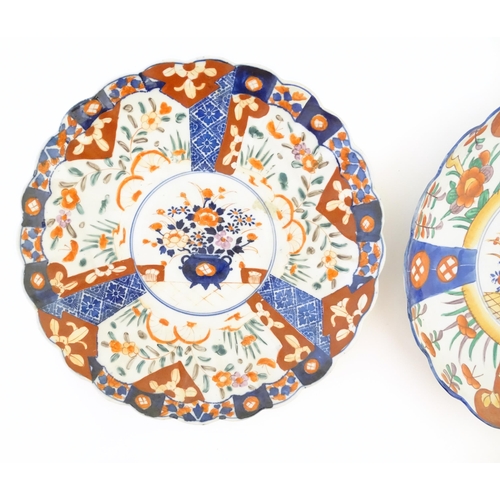 379 - Two Japanese chargers with scalloped edges decorated in the Imari palette depicting flowers and foli... 