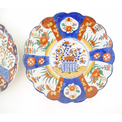 379 - Two Japanese chargers with scalloped edges decorated in the Imari palette depicting flowers and foli... 