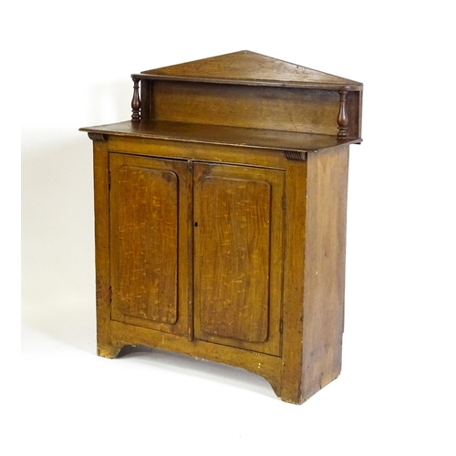 611 - A 19thC simulated oak chiffonier with a pointed upstand above turned supports and two panelled doors... 