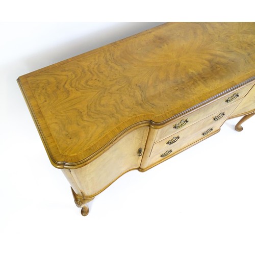 617 - An early / mid 20thC Waring & Gillows walnut sideboard with a serpentine shaped front and a crossban... 