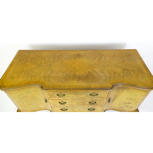 617 - An early / mid 20thC Waring & Gillows walnut sideboard with a serpentine shaped front and a crossban... 