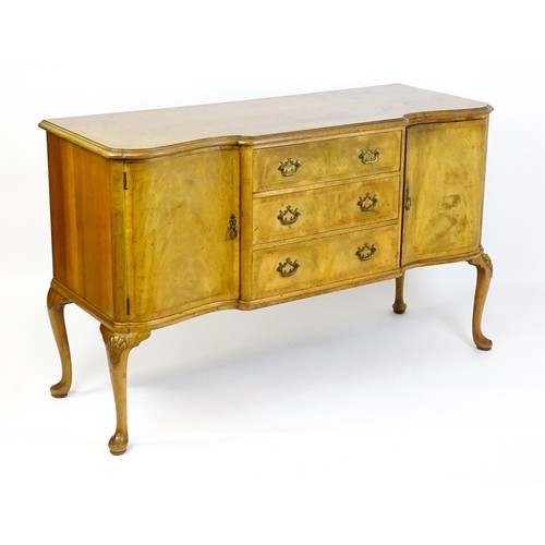 617 - An early / mid 20thC Waring & Gillows walnut sideboard with a serpentine shaped front and a crossban... 