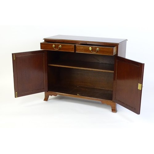 635 - A mahogany cabinet with a moulded top above two short drawers and two panelled cupboard, the cabinet... 