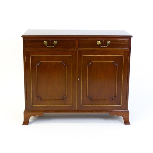 635 - A mahogany cabinet with a moulded top above two short drawers and two panelled cupboard, the cabinet... 