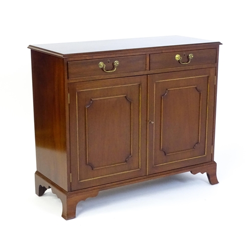 635 - A mahogany cabinet with a moulded top above two short drawers and two panelled cupboard, the cabinet... 