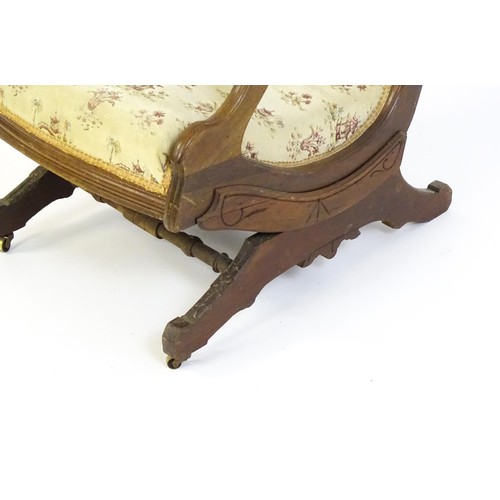 643 - An early 20thC rocking chair with carved cresting rail above a chamfered frame, with upholstered bac... 