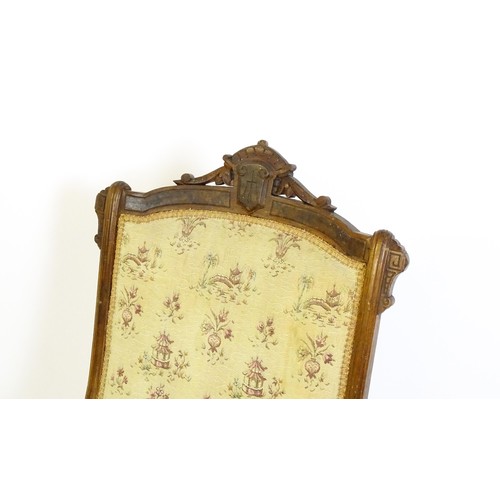 643 - An early 20thC rocking chair with carved cresting rail above a chamfered frame, with upholstered bac... 