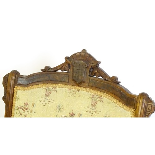 643 - An early 20thC rocking chair with carved cresting rail above a chamfered frame, with upholstered bac... 