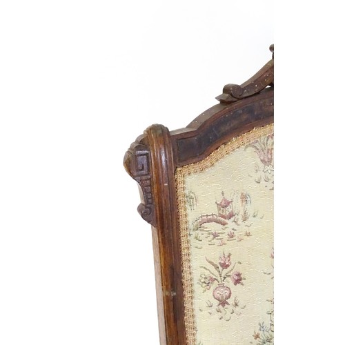 643 - An early 20thC rocking chair with carved cresting rail above a chamfered frame, with upholstered bac... 